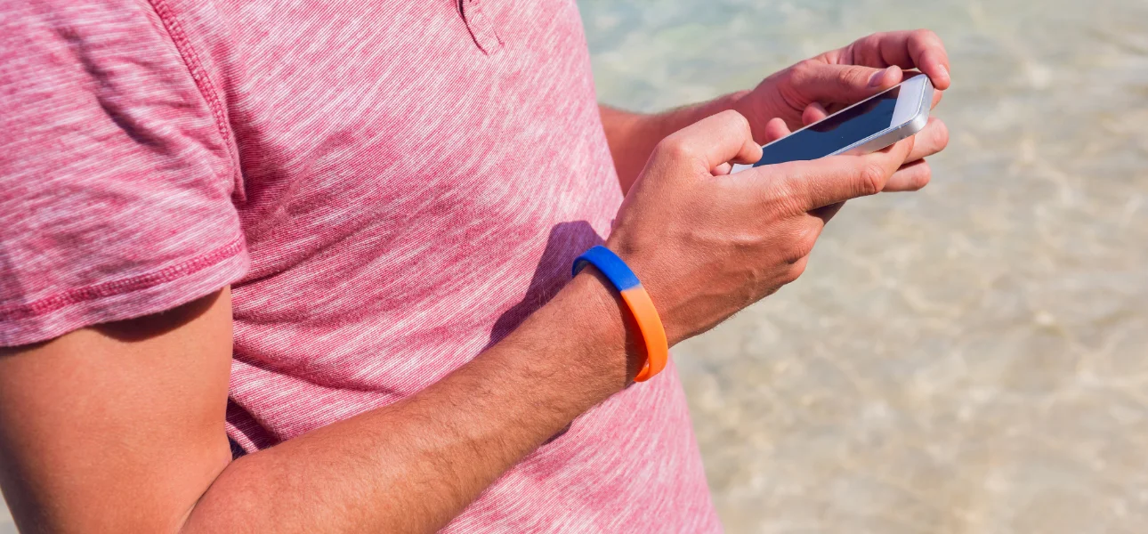 Hombre usando pulsera de silicona mientras usa su teléfono